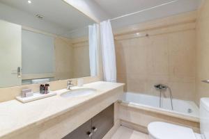 een badkamer met een wastafel, een bad en een spiegel bij Panoramic 1BR Apartment near Kallimarmaro Stadium by UPSTREET in Athene
