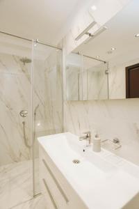 a white bathroom with a sink and a mirror at Beachfront luxury apartment in Budva