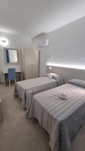 una camera con due letti e un tavolo con una sedia di ValGiuSi Resort a Capo Vaticano