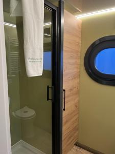 a bathroom with a toilet and a glass door at Hausboot mit Motorboot in Heiligenhafen