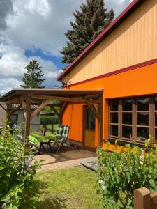 an orange building with a bench and a picnic table at Abendsonne in Mirow