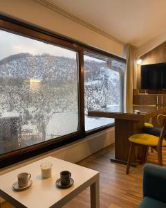 una stanza con una grande finestra con due tazze sul tavolo di Angela Apartment a Mavrovo