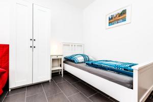 a white bedroom with a bed and a cabinet at Messewohnung Buchforst in Cologne