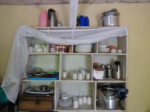 a kitchen shelf with dishes and utensils at Rwenzori Turaco View Camp in Kasese