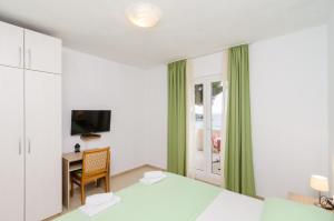 a bedroom with a bed and a desk and a television at Apartments Feral in Saplunara