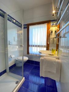 e bagno piastrellato blu con doccia e servizi igienici. di Il Ghebo a Cavallino-Treporti