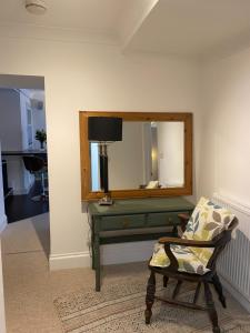 Cette chambre comprend un miroir, une chaise et un bureau. dans l'établissement Sandsifter at 4 Trencrom Court, Carbis Bay,St Ives, Cornwall, à Carbis Bay