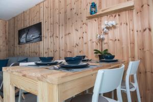 a dining room table with chairs and a wooden wall at Baltica Mielenko - domki apartamentowe nad morzem in Mielenko