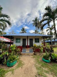 a house with a blue roof and some palm trees at Hill Myna Beach Cottages in Sabang