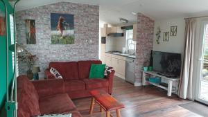 uma sala de estar com um sofá vermelho e uma parede de tijolos em dutchduochalet13 em s-Gravenzande