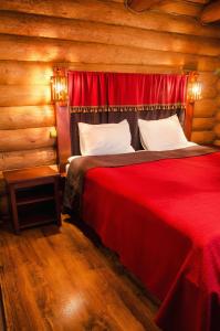 a bedroom with a red bed in a log cabin at Praha Wood House in Uzhhorod