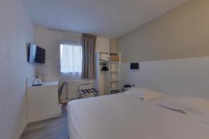 a hotel room with a white bed and a window at Hotel The Originals Bernay Acropole in Bernay