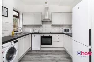 a kitchen with white cabinets and a washer and dryer at Host Liverpool - Spacious family home pets welcome in Liverpool