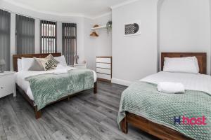 two beds in a room with white walls and wooden floors at Host Liverpool - Spacious family home pets welcome in Liverpool