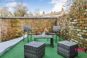 a patio with chairs and a table and a brick wall at Host Liverpool - Spacious family home pets welcome in Liverpool