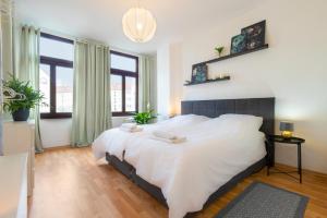 Schlafzimmer mit einem großen weißen Bett und Fenstern in der Unterkunft Ruhige Wohnung in zentraler Lage - Quiet flat in a central location in Magdeburg