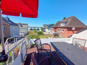 einen Balkon mit 2 Stühlen, einem Tisch und einem Sonnenschirm in der Unterkunft Ferienhaus Kassiopeia in Laboe