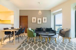 een woonkamer met een bank en tafels en stoelen bij Maison Privee - 5 Stars Apt in Architectural Marvel of Dubai in Dubai
