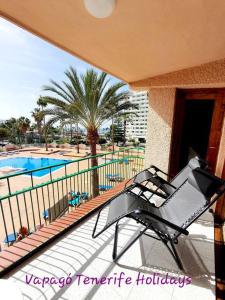 una silla en un balcón junto a la piscina en Lovely apartment in Costa Adeje, en Playa Fañabe