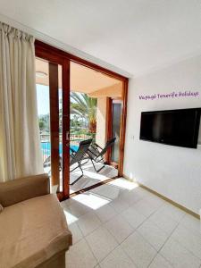 sala de estar con sofá y TV de pantalla plana en Lovely apartment in Costa Adeje, en Playa Fañabe