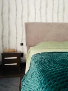 - une chambre avec un lit vert et une table de nuit dans l'établissement Aparthotel City Center Targu Ocna, à Tîrgu Ocna
