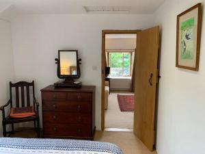 a bedroom with a bed and a mirror on a dresser at Chough Cottage: peace in a gorgeous, rural setting in Helston