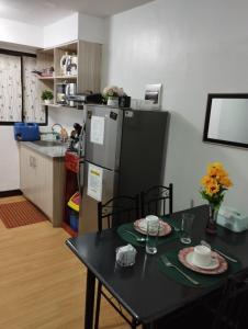 a kitchen with a table and a refrigerator at Drea Staycation 2 Bedroom at Urban Deca Homes Marilao in Marilao
