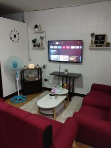 a living room with a red couch and a tv at Drea Staycation 2 Bedroom at Urban Deca Homes Marilao in Marilao