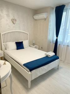 ein Schlafzimmer mit einem Bett mit einer blauen Decke und einem Fenster in der Unterkunft Jadore in Weliko Tarnowo