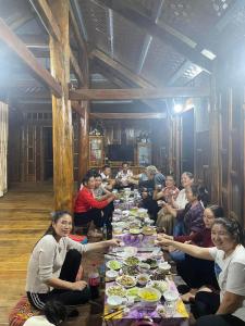 un grupo de personas sentadas alrededor de una larga mesa con comida en Nhà nghỉ Tâm Cường en Diện Biên Phủ