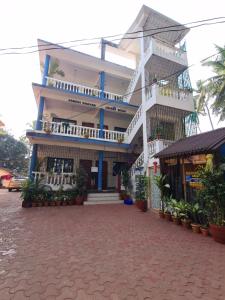 a large white building with balconies on a street at Palolem Sunrise Apartment in Palolem