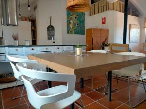 cocina con mesa de madera y sillas blancas en El Telar Arte y Naturaleza, en Prádena