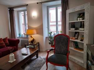 ein Wohnzimmer mit einem roten Stuhl und einem Tisch in der Unterkunft Les Chambres Hautes d'Anastasia in Rodez