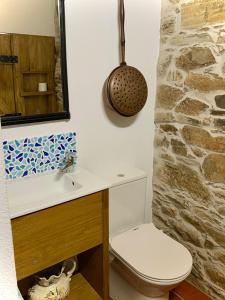 a bathroom with a toilet and a sink and a stone wall at Casa Da Oliveira in Pedrógão Grande