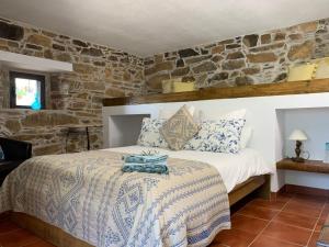 a bedroom with a bed and a stone wall at Casa Da Oliveira in Pedrógão Grande