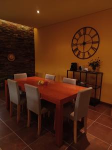 ein Esstisch mit Stühlen und eine Uhr an der Wand in der Unterkunft Alegre moradia in Perozinho