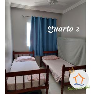 two beds in a room with blue curtains at Ap Privativo Jockey, uma quadra da praia, Sentir-se em casa! in Vila Velha