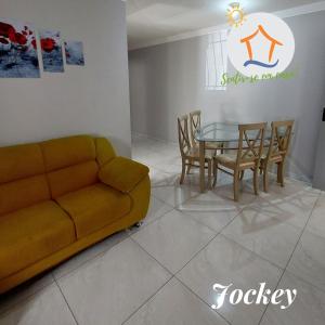 uma sala de estar com um sofá, uma mesa e cadeiras em Ap Privativo Jockey, uma quadra da praia, Sentir-se em casa! em Vila Velha