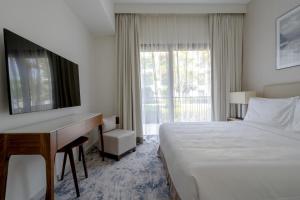 Habitación de hotel con cama, escritorio y ventana en Alnoon at Address Beach Resort Fujairah, en Sharm