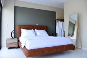 um quarto com uma cama grande com lençóis brancos e um espelho em Spacious & Minimal Apartment Near Airport Peania Coniann Filoxenia em Paianía