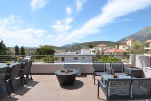 a patio with tables and chairs on a balcony with mountains at Spacious & Minimal Apartment Near Airport Peania Coniann Filoxenia in Paianía