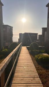 een houten promenade die naar het strand leidt met de zon op de achtergrond bij Pichilemu Loft 51 in Pichilemu
