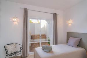 une chambre avec un lit, une fenêtre et une chaise dans l'établissement Casa da Tia, à Luz