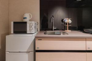 a kitchen with a sink and a microwave at Apartment Hotel 11 Namba in Osaka