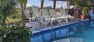a group of chairs sitting on a deck next to a swimming pool at Serena Aparts in La Paloma