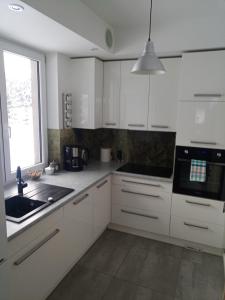 uma cozinha com armários brancos, um lavatório e uma janela em Dom nad Bliznem em Walne