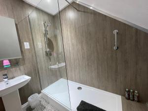 La salle de bains est pourvue d'une douche avec une porte en verre. dans l'établissement Cotswold Hare, à Cirencester