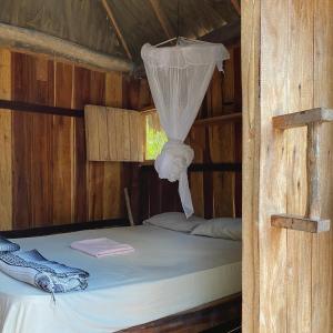 Ce lit se trouve dans une cabane en bois dotée d'une moustiquaire. dans l'établissement Balam Camping & cabañas, à Holbox