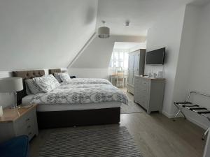 a white bedroom with a bed and a desk at Cotswold Hare in Cirencester