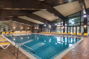 une grande piscine avec des chaises et des tables dans l'établissement Hotel Pirin, à Bansko